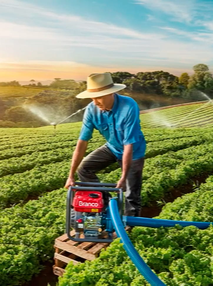 Foto de um agricultor utilizando um equipamento da marca Branco para irrigação em uma lavoura.