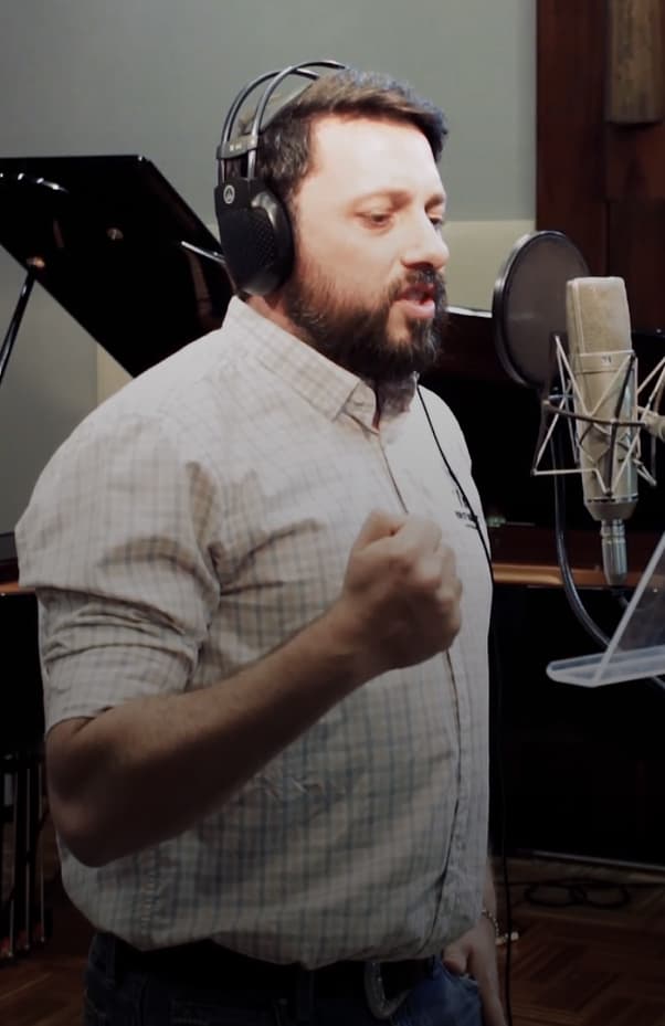 Cantor com fones de ouvido em um estúdio e um microfone profissional.